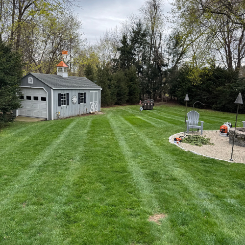 Gray shed in well-maintained backyard with freshly mowed green lawn