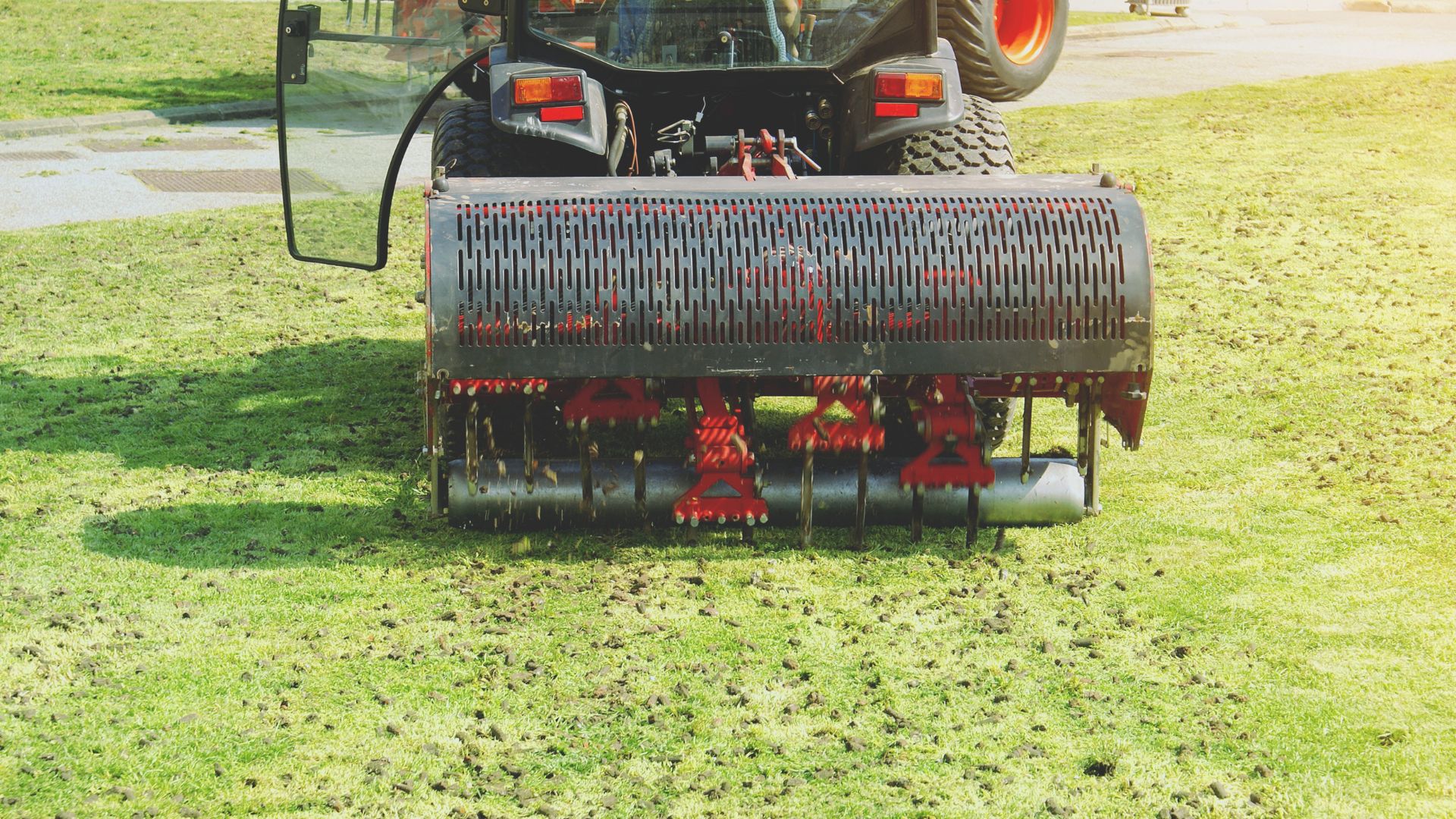Agricultural machine aerating lawn with perforated roller attachment