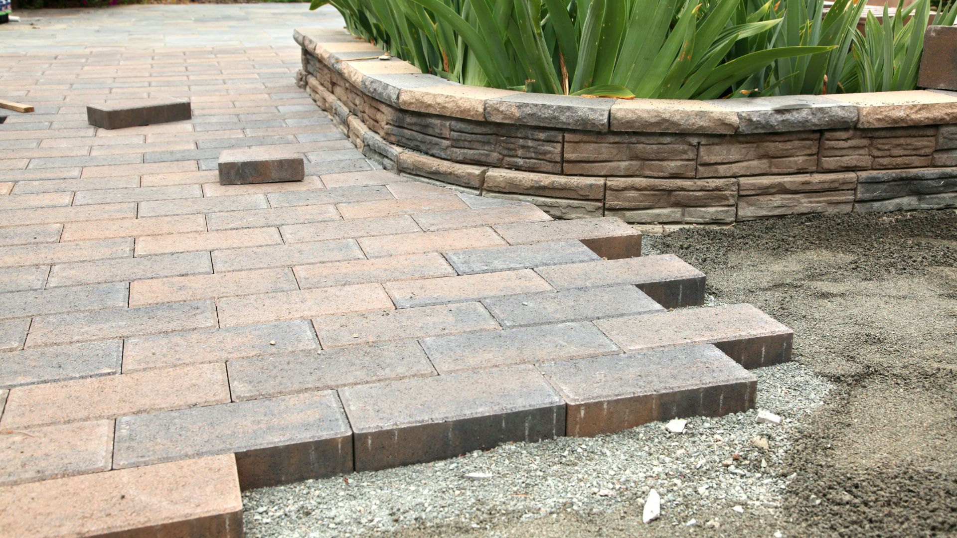 Stone paver walkway with curved retaining wall and green plants