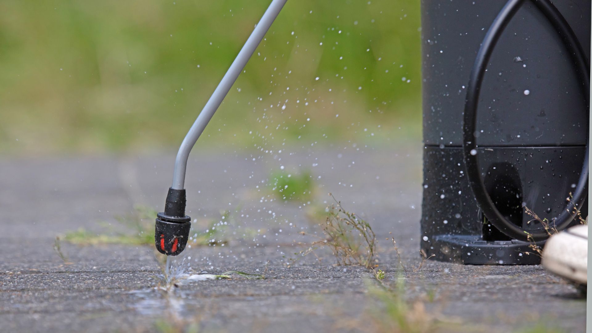 Water spraying from pressure washer nozzle on concrete ground